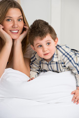 Happy young mother and her cute son playing at home