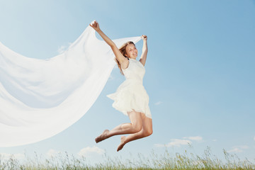 Fototapeta na wymiar The young beautiful girl in a white dress enjoys a wind, the sun