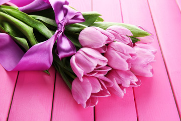 Beautiful bouquet of purple tulips on pink wooden background