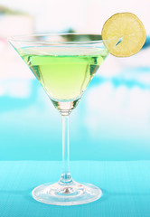Green cocktail with lime on table on bright background