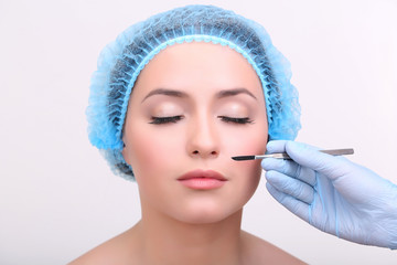 Cosmetic surgery with scalpel on young woman close up