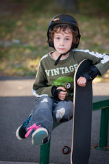young boy wearing safty equipment learning to skateboard