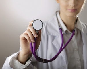 A young female doctor listening, isolated on grey background