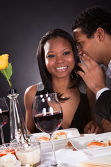 Man Whispering To Girlfriend's Ear