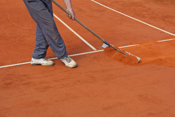Repairing tennis court, worker fixes the lines on tennis courts