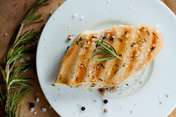 Grilled chicken breast with rosemary on white plate