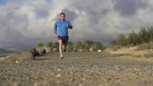 Man jogging in on dirt track, super slow motion