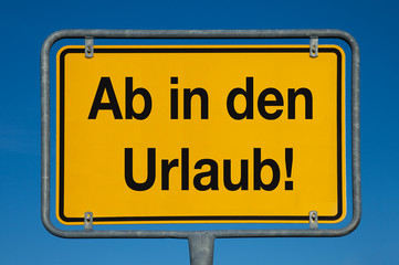 Ortsschild mit blauem Himmel AB IN DEN URLAUB!