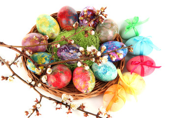 Beautiful Easter eggs in wicker basket isolated on white
