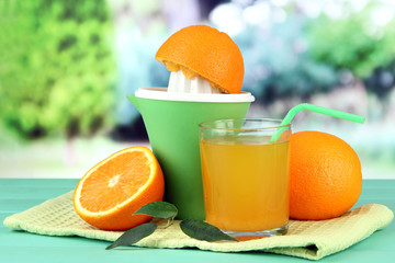 Citrus press, glass of juice and ripe oranges