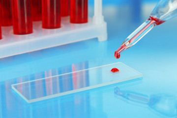 Test tubes with blood in laboratory on blue background
