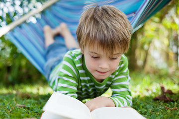 kleiner junge liest im garten