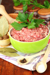 Bowl of raw ground meat with spices on wooden table