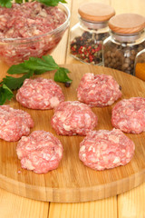 Raw meatballs with spices on wooden table