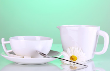 A cup of strong coffee and sweet cream on green background