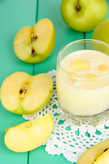 Delicious yogurt in glass with apple on wooden table close-up