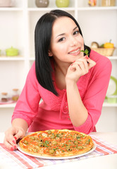 Beautiful girl with delicious pizza on kitchen background