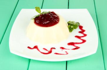 Panna Cotta with raspberry sauce, on color wooden background