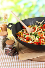 Noodles with vegetables on wok on nature background