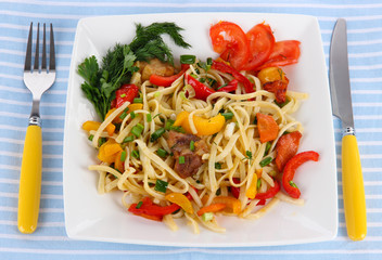Noodles with vegetables on plate on napkin isolated on white
