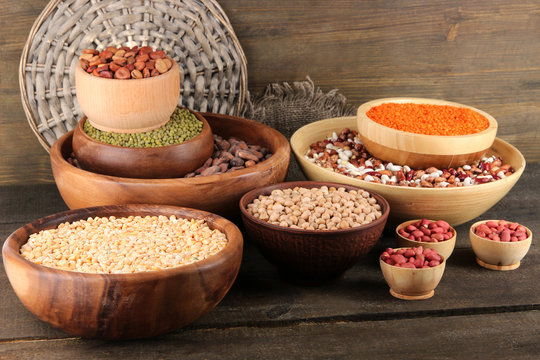 Different kinds of beans in bowls on wooden background