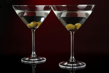 Martini glasses with olives on dark red background