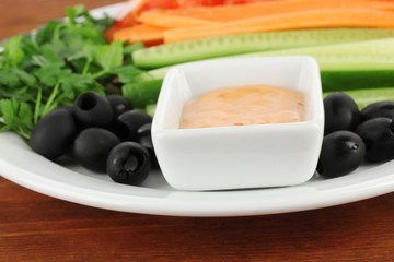 Assorted raw vegetables sticks in plate on wooden table close