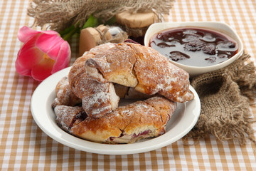 Taste croissants on plate and jam on tablecloth.