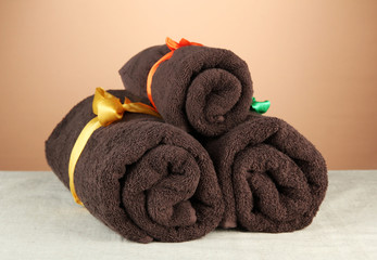 Obraz na płótnie Canvas Three rolled towels, on brown background