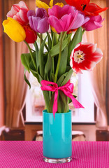 Beautiful tulips in bouquet on table in room