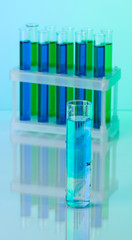 Identical test tubes and hand on blue background