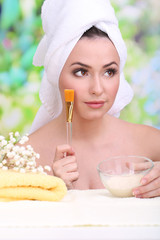 Obraz na płótnie Canvas Beautiful young woman with cream for face mask towel