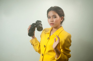 Pretty young Asian businesswoman  holding a binoculars.