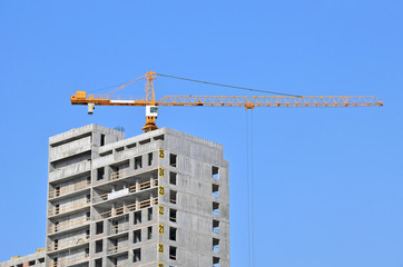 Building crane and building under construction against blue sky