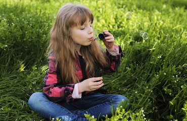 Little girl blowing soap bubbles in the park