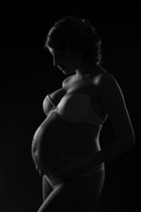 Beautiful pregnant woman silhouette over black background