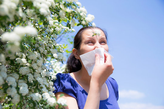 Allergic woman sneezing in handkerchief