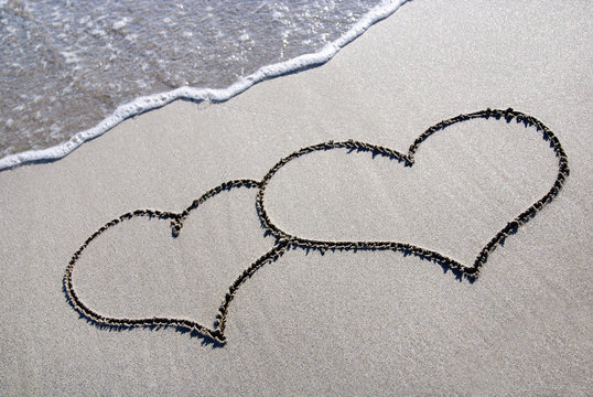 heart outline on beach sand with wave
