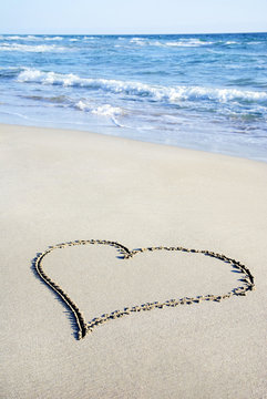 heart outline on sand against wave
