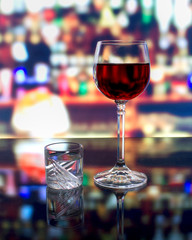 A glass of wine and a shot of vodka on the bar counter