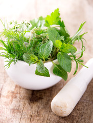 Mortar with herbs on wooden table