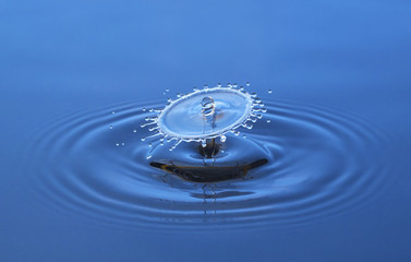 Drop falling in water, blue background