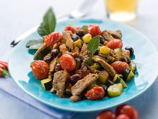 meat stew with tomatoes zucchinis and olives, selective focus