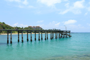 Fototapeta na wymiar Wooden footbridge over the water near the beach