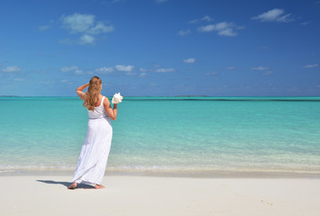 Fototapeta na wymiar Girl with a shell in the hand on the beach of Exuma, Bahamas