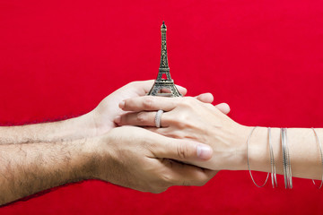 Manos de hombre y mujer sujetan una pequeña torre Eiffel