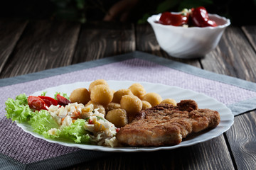Breaded chop, prepared potatoes and salad. Mysterious light