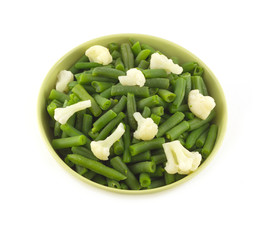Green beans and cauliflower in green bowl isolated on white