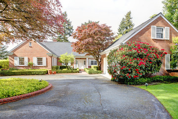 Brick red house with English garden and white window shutters.