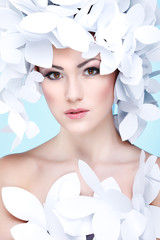 Wonderful girl in a hat from paper white butterflies on a blue 